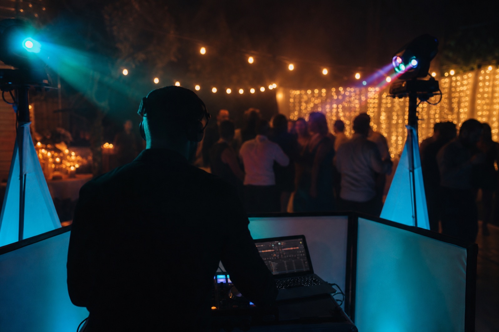 Cabina de DJ móvil en una fiesta privada con luces de cadena y un haz cian